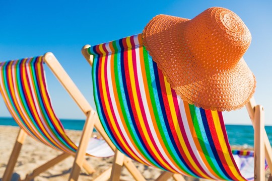 Oranje strandhoed aan gekleurde strandstoel op strand